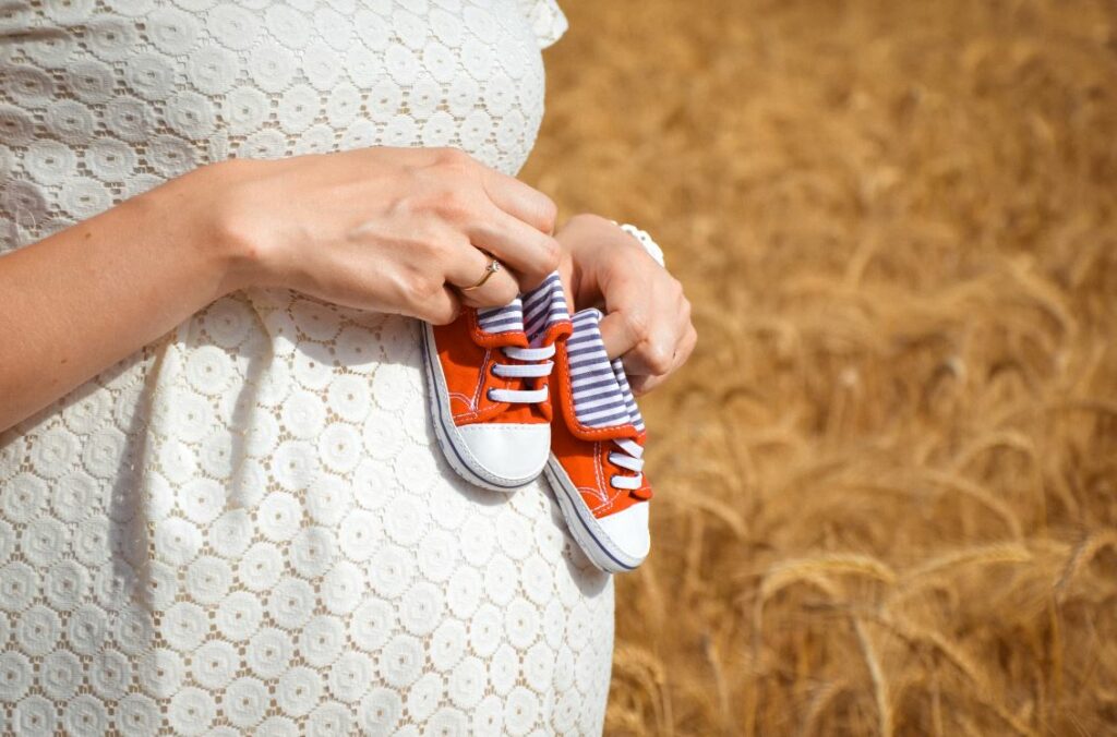 femme enceinte tenant des chaussures d'enfants